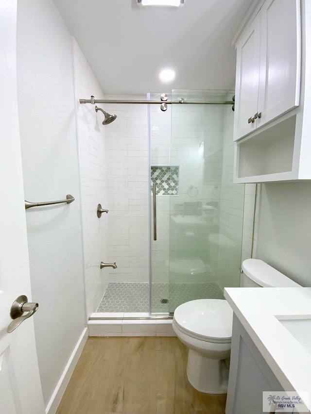 full bath with vanity, a stall shower, wood finished floors, and toilet