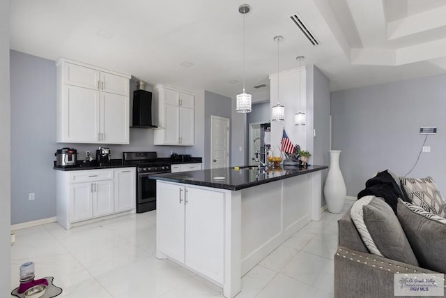 9129 Lake Charles Dr, Los Fresnos, TX 78566 - kitchen with stainless steel gas stove, wall chimney exhaust hood, light marble finish floors, white cabinetry, and dark countertops