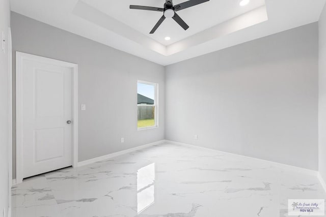 empty room featuring a tray ceiling and ceiling fan