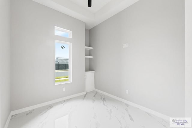 unfurnished room featuring built in shelves and ceiling fan