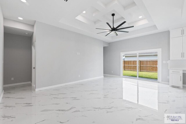 empty room featuring a raised ceiling, coffered ceiling, and ceiling fan