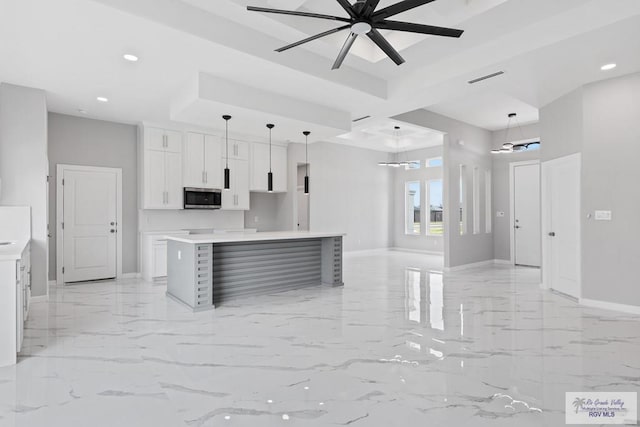 kitchen featuring ceiling fan, decorative light fixtures, a center island, and white cabinets