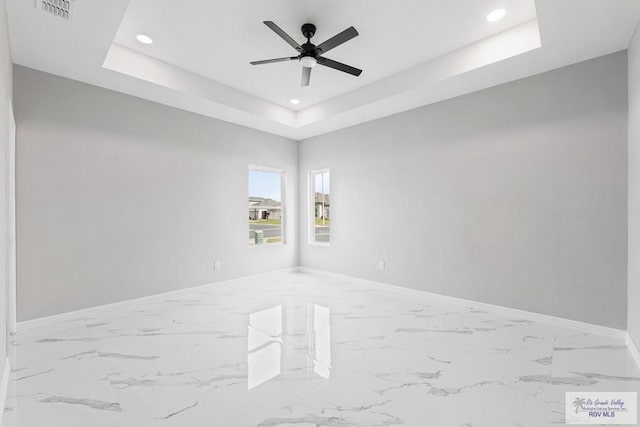 empty room featuring ceiling fan and a tray ceiling