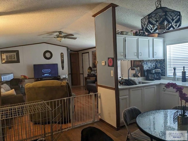 kitchen featuring white cabinets, a textured ceiling, sink, and vaulted ceiling