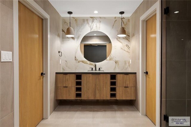 bathroom with decorative backsplash, tile patterned flooring, vanity, and tile walls