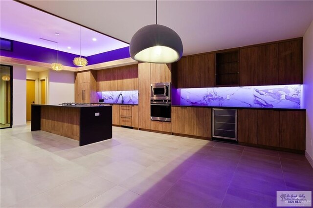 kitchen with a center island, beverage cooler, stainless steel appliances, and decorative light fixtures