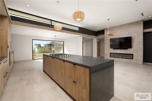 kitchen with a spacious island, ceiling fan, hanging light fixtures, and stainless steel gas cooktop