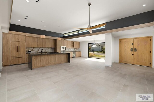 kitchen featuring decorative backsplash, stainless steel microwave, a center island, and decorative light fixtures