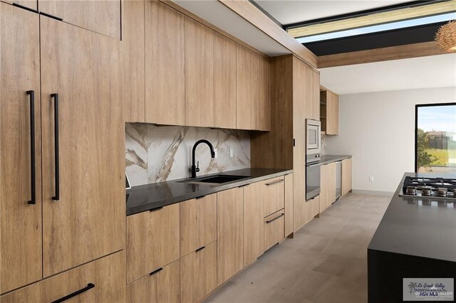 kitchen with light brown cabinetry, decorative backsplash, sink, and appliances with stainless steel finishes