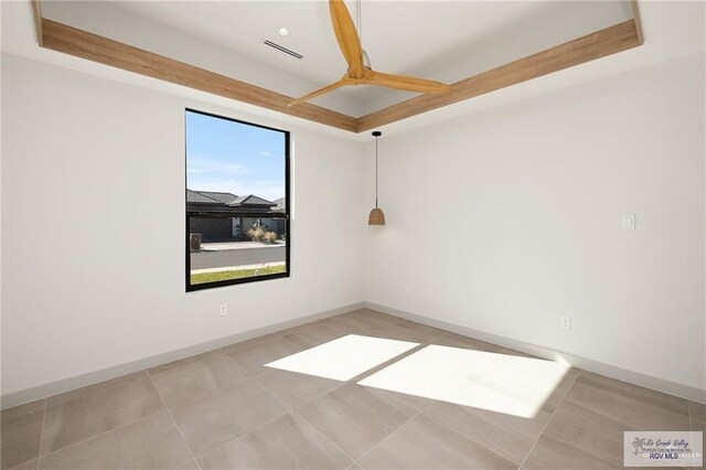 empty room featuring tile patterned floors and a raised ceiling