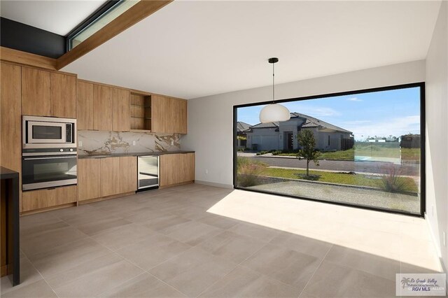 kitchen with pendant lighting, backsplash, wine cooler, light tile patterned floors, and stainless steel appliances