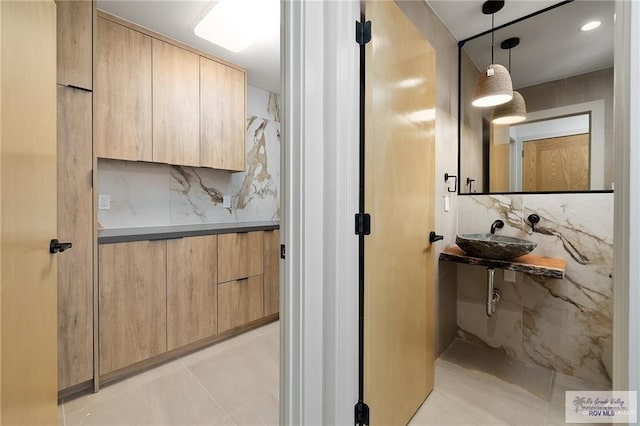 bathroom with tile patterned flooring, sink, and tasteful backsplash