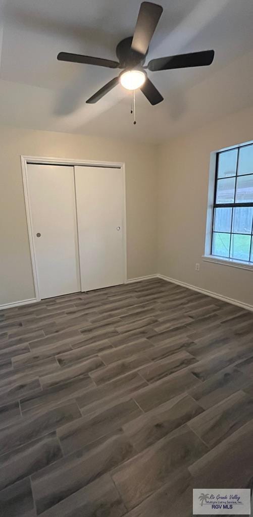 unfurnished bedroom with ceiling fan, dark hardwood / wood-style floors, and a closet