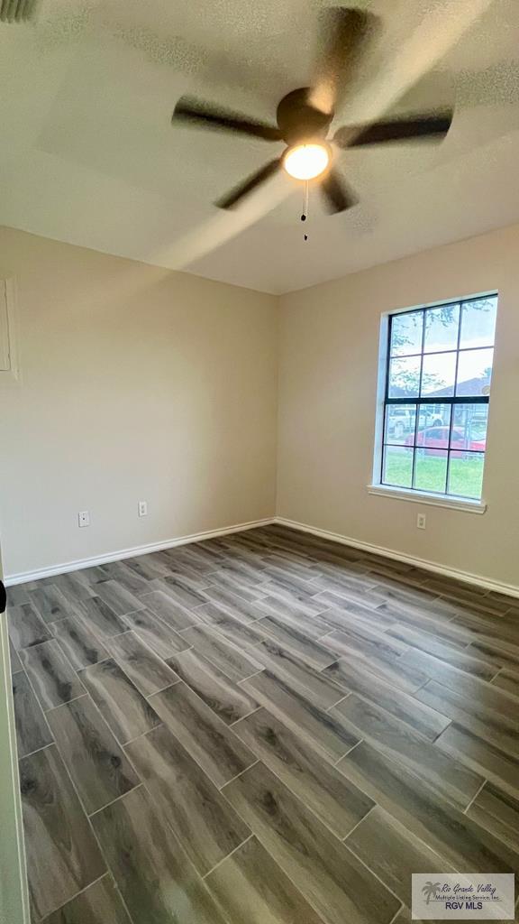 spare room with a textured ceiling, dark hardwood / wood-style flooring, and ceiling fan