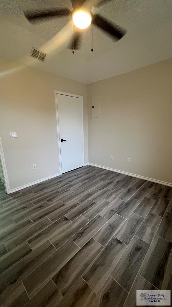 unfurnished room featuring dark hardwood / wood-style floors, ceiling fan, and a textured ceiling