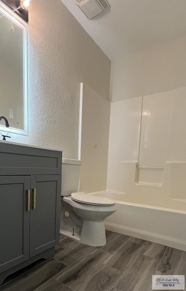 full bathroom with shower / bathing tub combination, wood-type flooring, vanity, and toilet