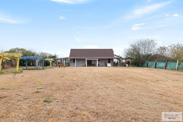 back of property featuring a yard and a pergola