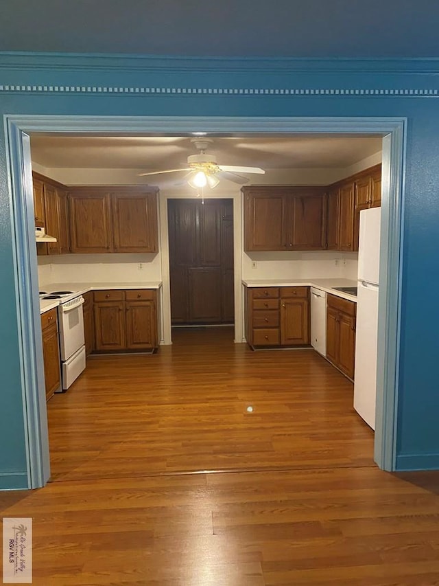 kitchen featuring a ceiling fan, white appliances, brown cabinetry, and wood finished floors