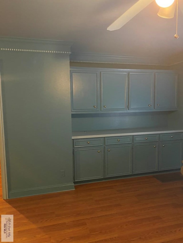 kitchen featuring green cabinets, light countertops, baseboards, and wood finished floors