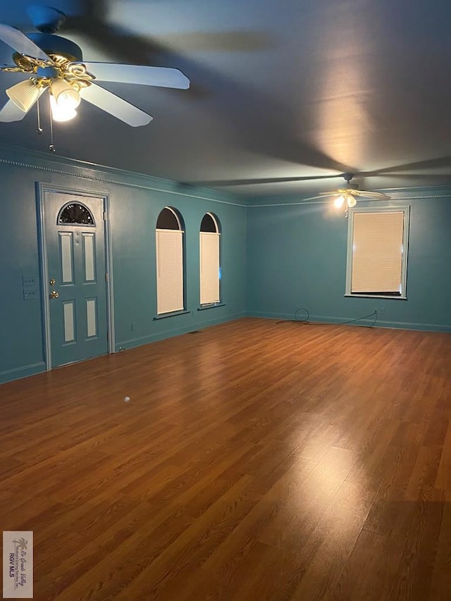 unfurnished room with a ceiling fan, crown molding, wood finished floors, and baseboards