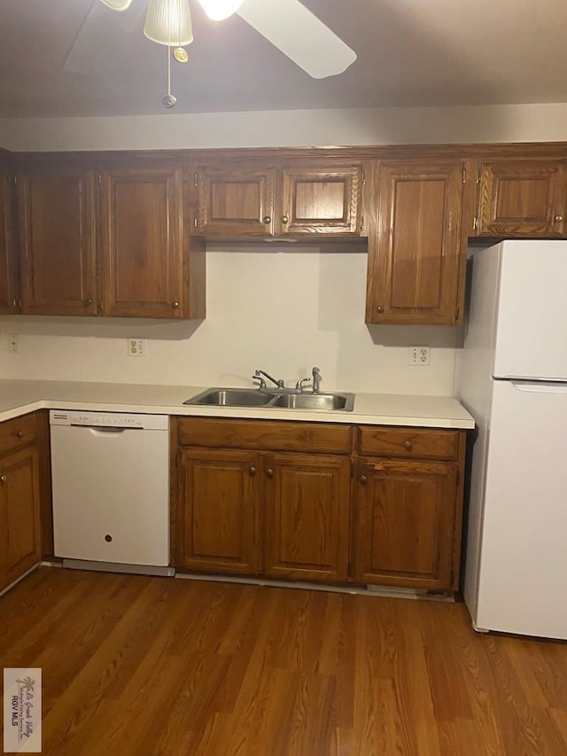 kitchen with dark wood-style flooring, white appliances, light countertops, and a sink