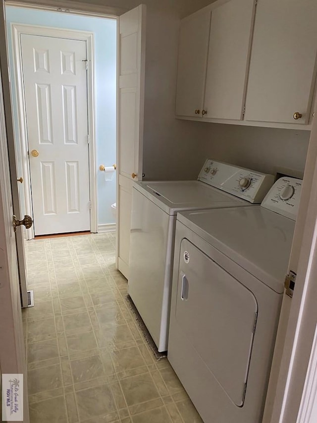 clothes washing area with washing machine and dryer, cabinet space, and light floors