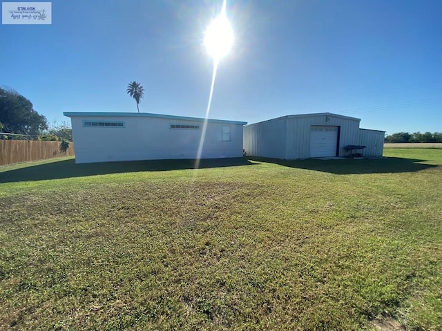 view of yard featuring a detached garage, an outbuilding, a pole building, and fence