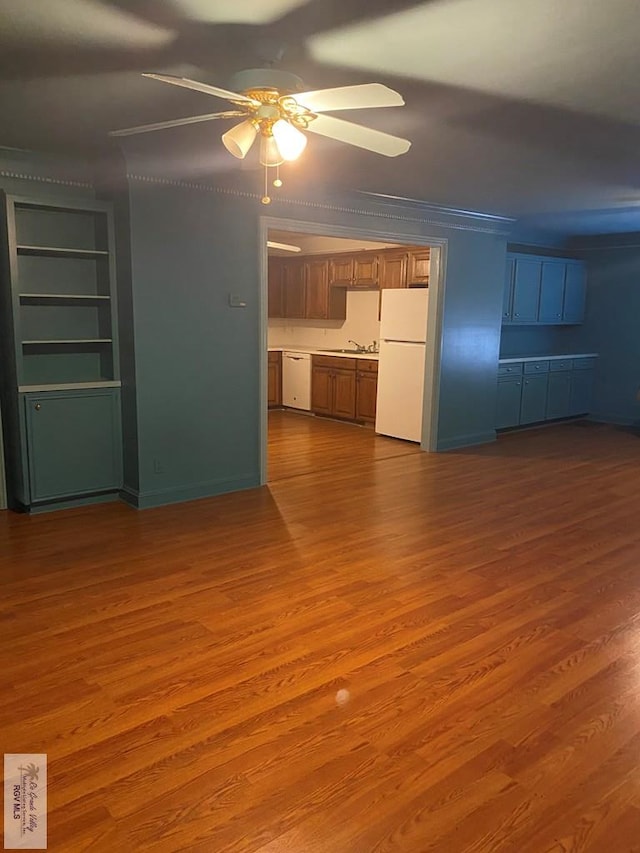 unfurnished living room featuring a sink, wood finished floors, ceiling fan, and ornamental molding