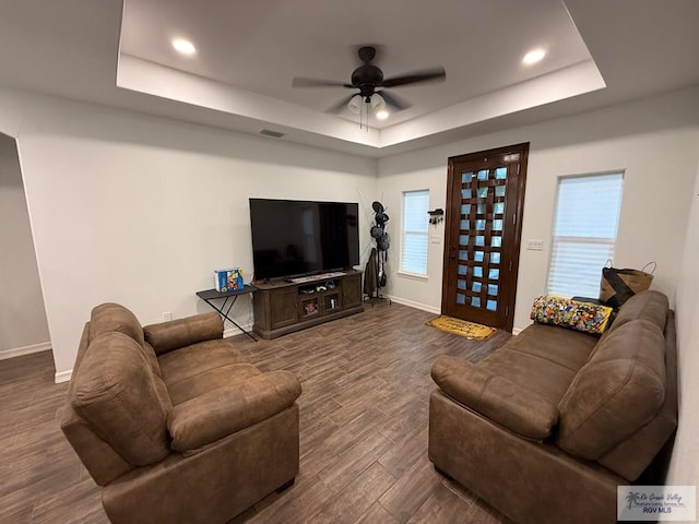 living room with ceiling fan, dark hardwood / wood-style floors, and a raised ceiling