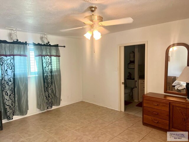 501 W Palm Valley Dr, Harlingen, TX 78552 - bedroom featuring light tile patterned floors, a textured ceiling, ensuite bath, and ceiling fan