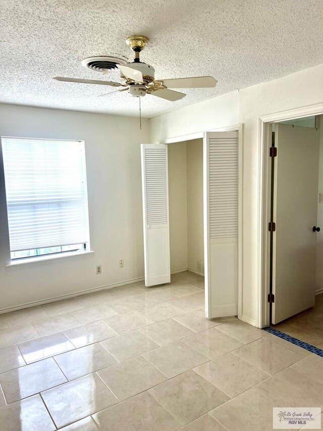 501 W Palm Valley Dr, Harlingen, TX 78552 - unfurnished bedroom featuring a textured ceiling, light tile patterned floors, a ceiling fan, a closet, and baseboards