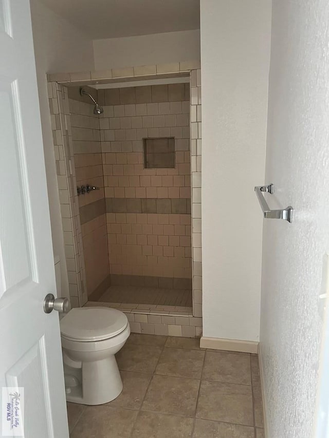 full bathroom featuring a stall shower, baseboards, tile patterned flooring, and toilet