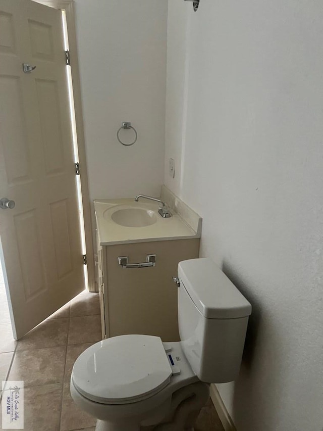 half bath featuring toilet, tile patterned flooring, and vanity