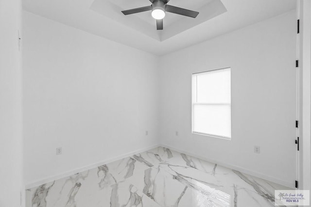 unfurnished room featuring ceiling fan and a raised ceiling