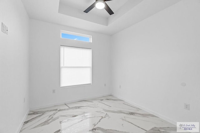 empty room featuring ceiling fan and a tray ceiling