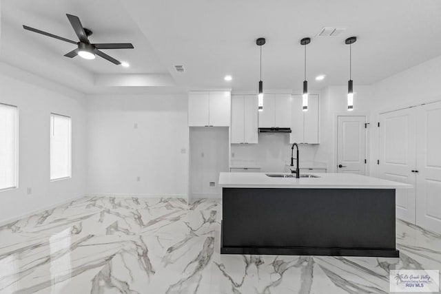 kitchen with sink, ceiling fan, white cabinets, a center island with sink, and decorative light fixtures