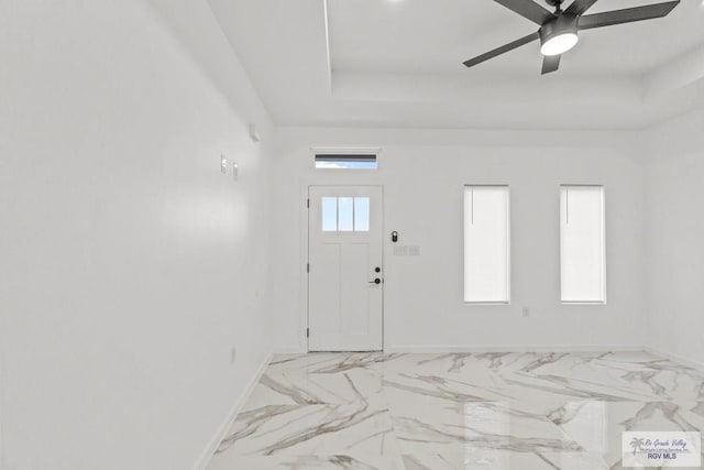 entrance foyer with ceiling fan and a tray ceiling