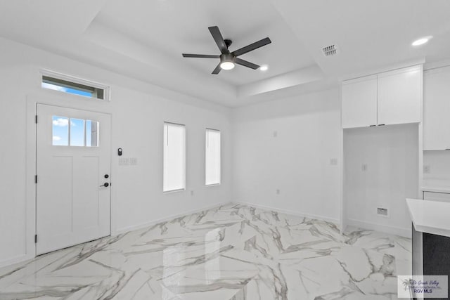 entrance foyer featuring a tray ceiling and ceiling fan