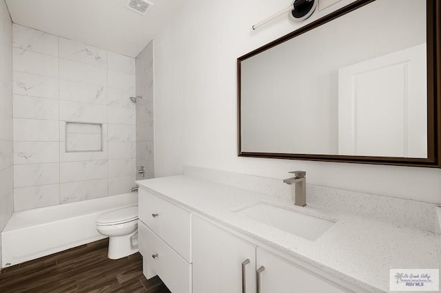 full bathroom with tiled shower / bath, toilet, vanity, and hardwood / wood-style flooring