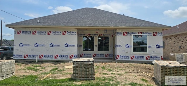 back of house with roof with shingles