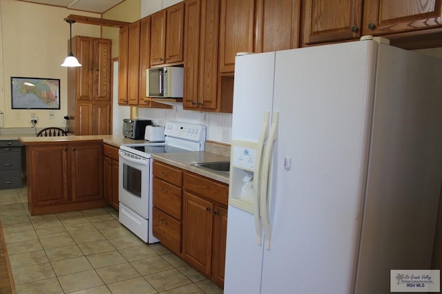 kitchen featuring tasteful backsplash, kitchen peninsula, pendant lighting, white appliances, and light tile patterned floors