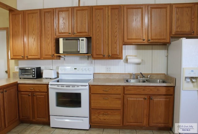 kitchen featuring sink, light tile patterned flooring, and white appliances