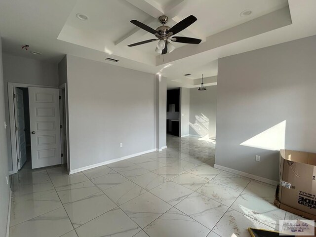 unfurnished room featuring ceiling fan and a tray ceiling