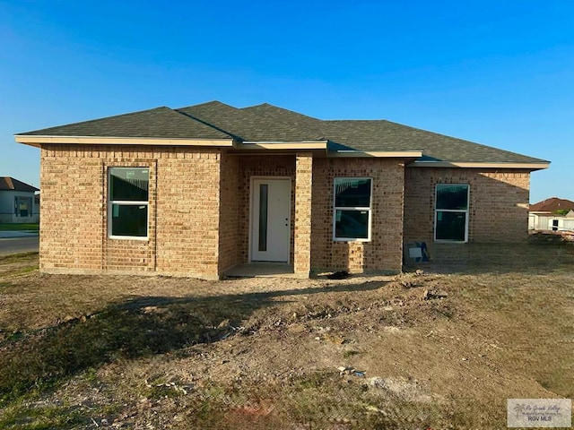view of front of house with brick siding and roof with shingles