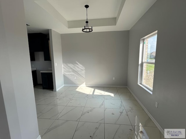 unfurnished dining area with a raised ceiling and plenty of natural light