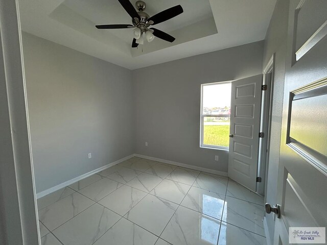 spare room featuring a raised ceiling and ceiling fan