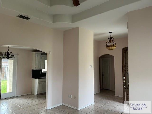 spare room with ceiling fan with notable chandelier and light tile patterned floors