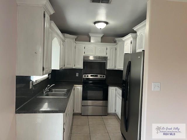 kitchen with appliances with stainless steel finishes, tasteful backsplash, white cabinetry, sink, and light tile patterned floors