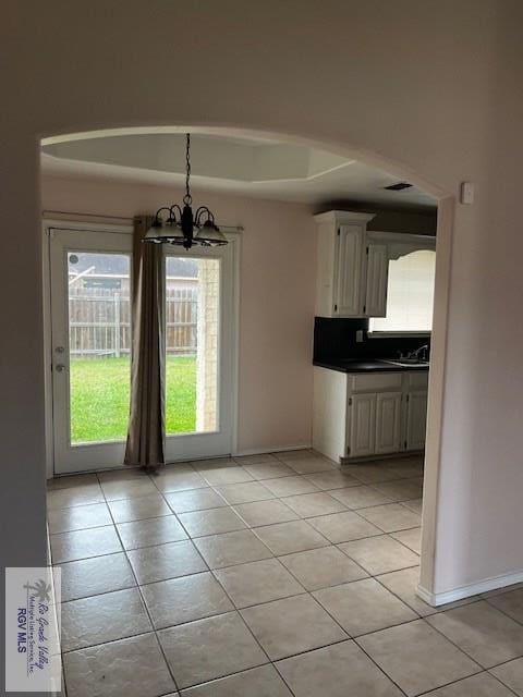 unfurnished dining area with sink, light tile patterned floors, and a chandelier