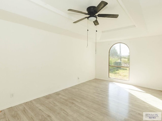 unfurnished room featuring a tray ceiling, ceiling fan, and light wood-type flooring